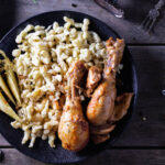 chicken drumsticks with egg noodles and pickles on a plate