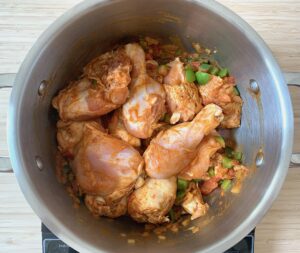 Chicken pieces in pot with pepper and tomato