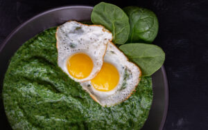 Creamed spinach and sunny side up eggs in a black bowl